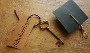 a key with a scholarship written on a brown paper with a graduation toga promoting chief chicago limo college scholarship program