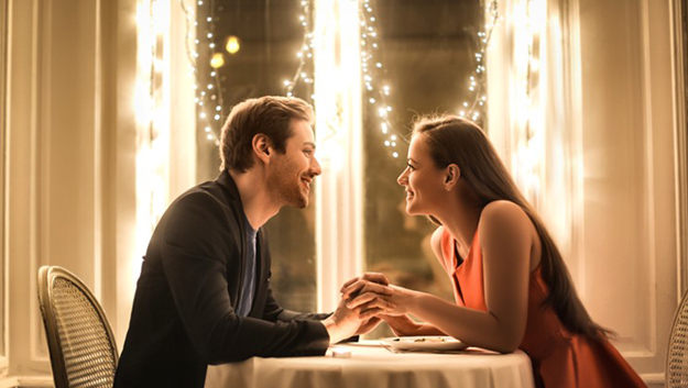 a couple with an happy face while holding each other hands and looking each other for a dinner limo service