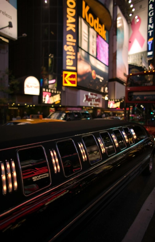 A black stretch limousine parked in a brightly lit city street at night illustrating Night On the Town Limousine