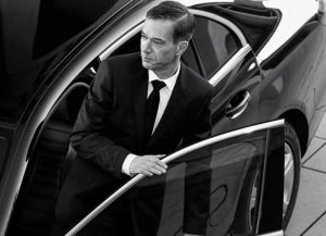 Well-dressed man exits high-end vehicle showcasing Chauffeur Service Chicago