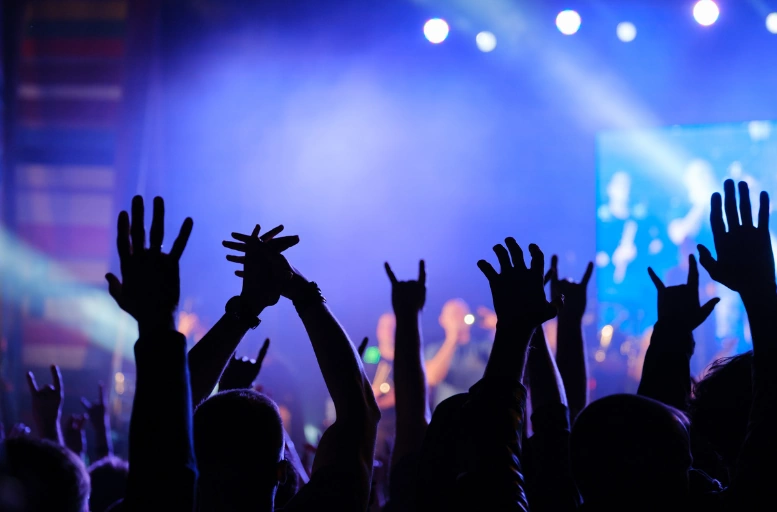 Concertgoers' raised hands against blue and purple stage lights after arriving in a luxury concert limo service Chicago