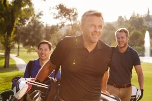 Three men walking across a golf course with bags, representing Golf Transportation Chicago services.